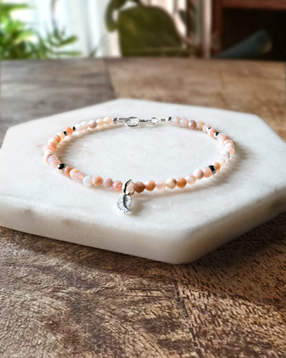Pale pink opal gemstone beaded bracelet with sterling silver leaf-shaped charm and spring ring clasp.