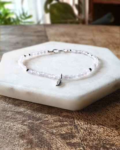 Pale pink rose quartz gemstone beaded bracelet with sterling silver leaf-shaped charm and spring ring closure.