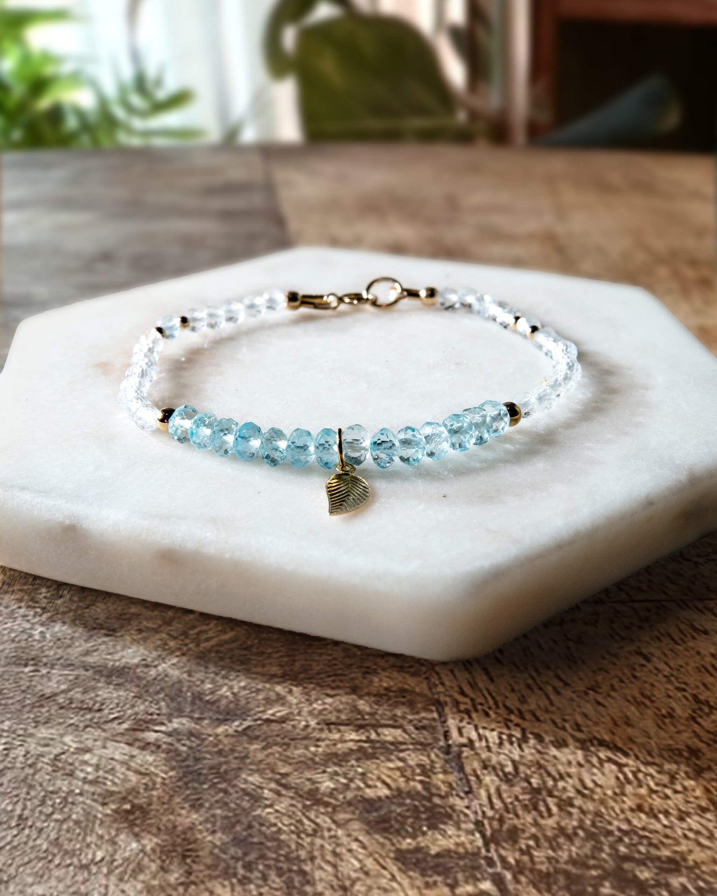 Blue and white topaz gemstone beaded bracelet with 14k gold-filled leaf-shaped charm and spring ring clasp.