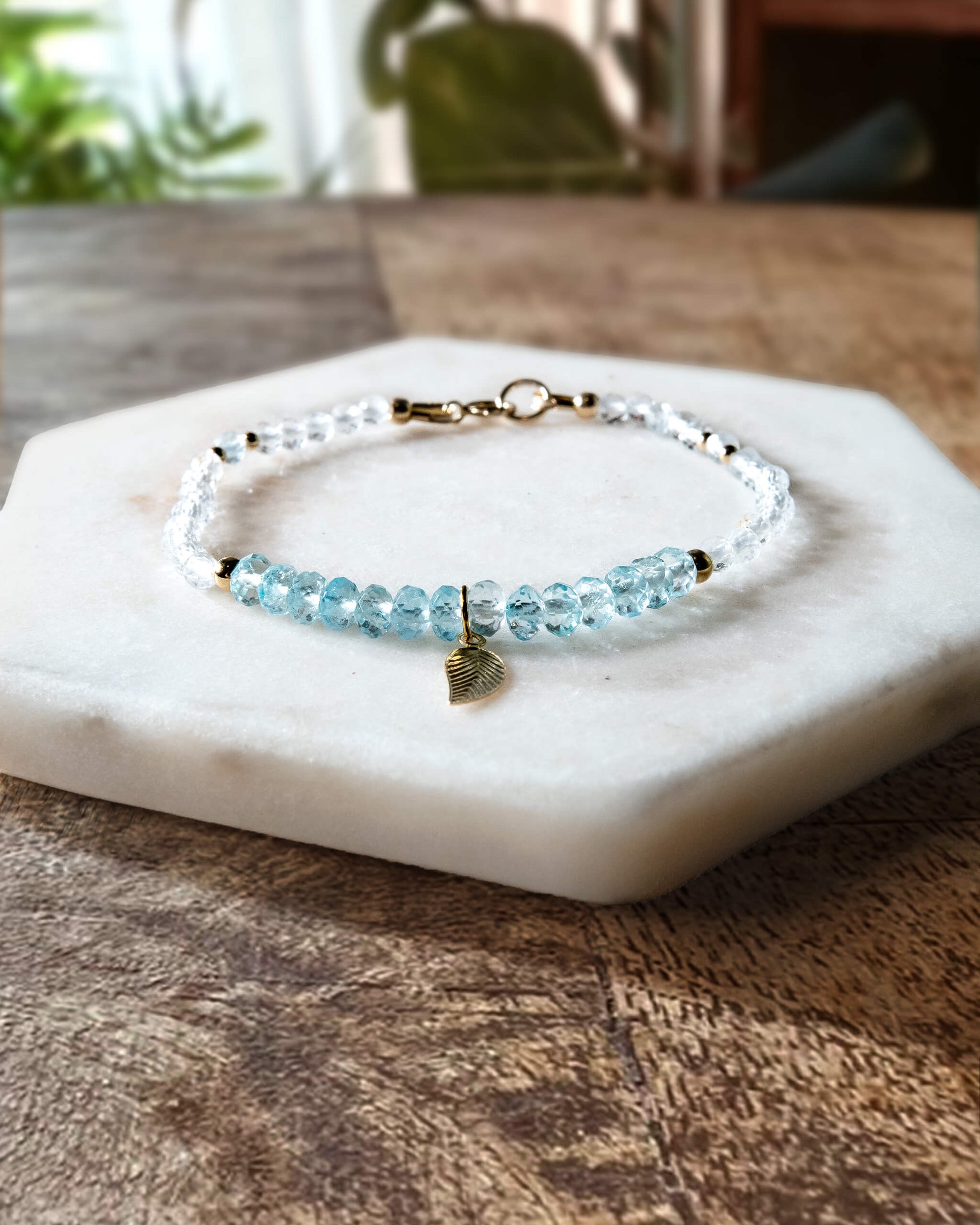 Blue and white topaz gemstone beaded bracelet with 14k gold-filled leaf-shaped charm and spring ring clasp.