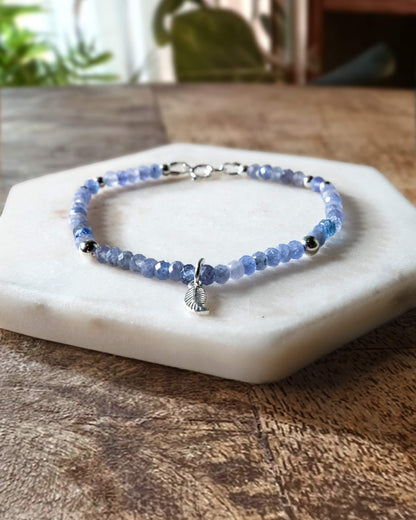 Periwinkle blue tanzanite gemstone beaded bracelet with sterling silver leaf-shaped charm and spring ring clasp.